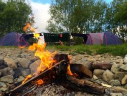 Tent site with campfire on the riverbank at Kaitoke Regional Park