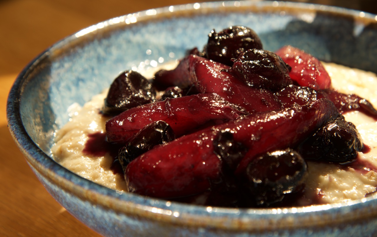 A blue pottery bowl of Pear & Cherry Compote with Creamy Porridge