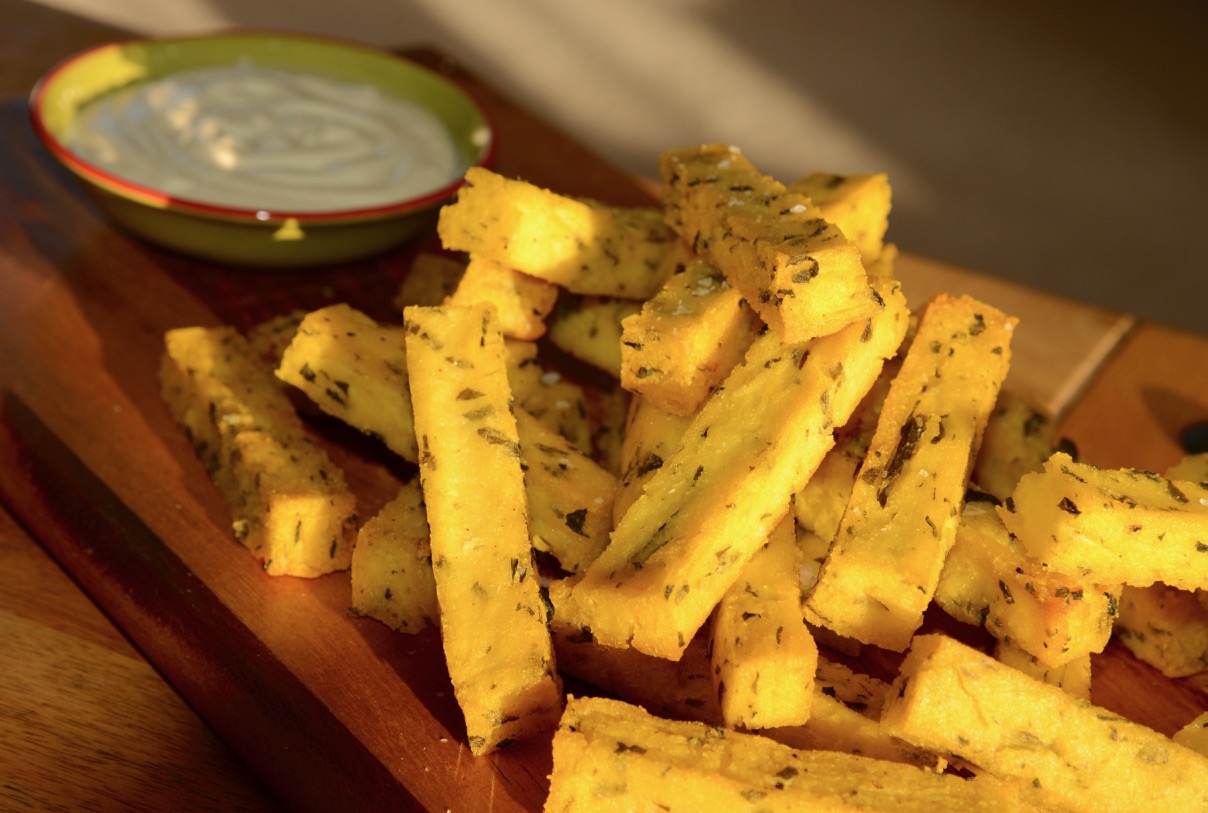 Baked polenta chips with tofu alioli on a wooden platter