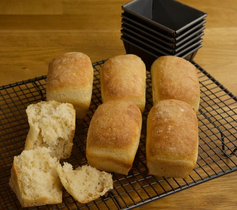 6 mini bread loaves cooling a baking rack.