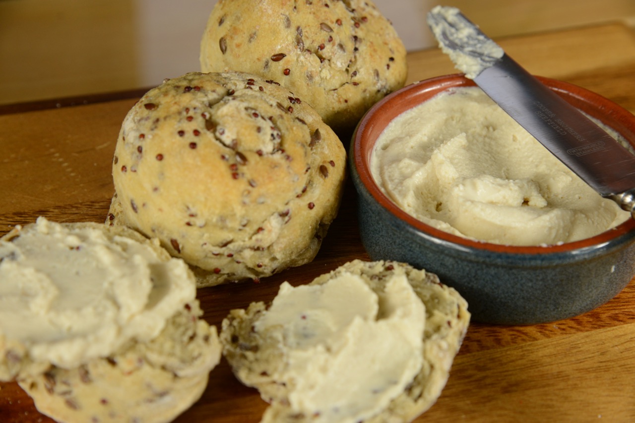 A bowl of freshly made Cashew Tofu cream cheese beside freshly baked seeded overnight bread.