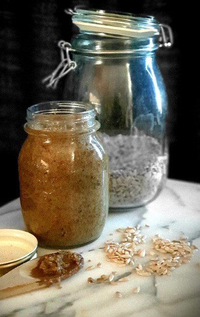 A jar of sunflower seed tahini and fresh sunflower seeds on a marble bench