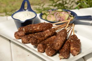 Platter with bbq'ed lentil and walnut kofte on skewers, herb cashew yoghurt and pickled cucumber and red onion