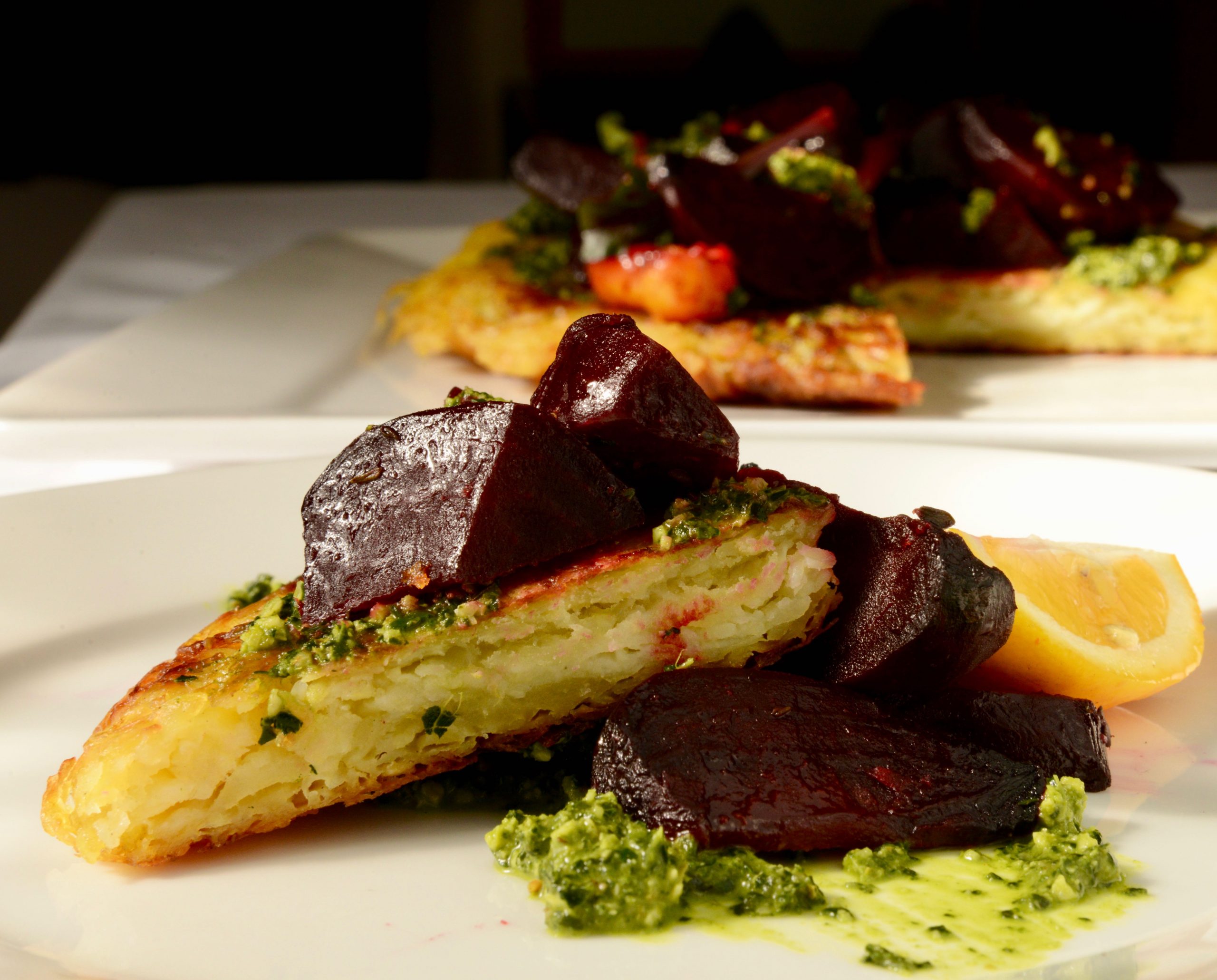 Wedge of potato roost topped with brown bag beets and kale and walnut pesto