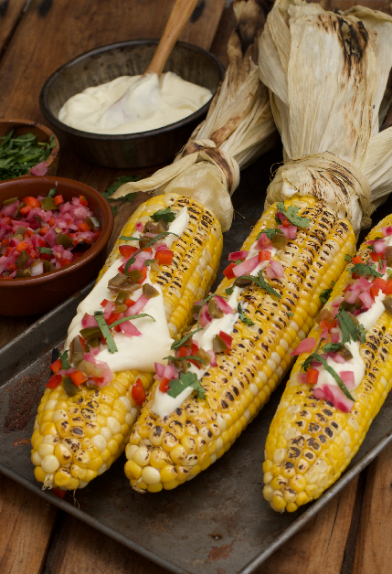3 Barbecued corn cobs garnished with mayo, jalapeño salas and chopped coriander